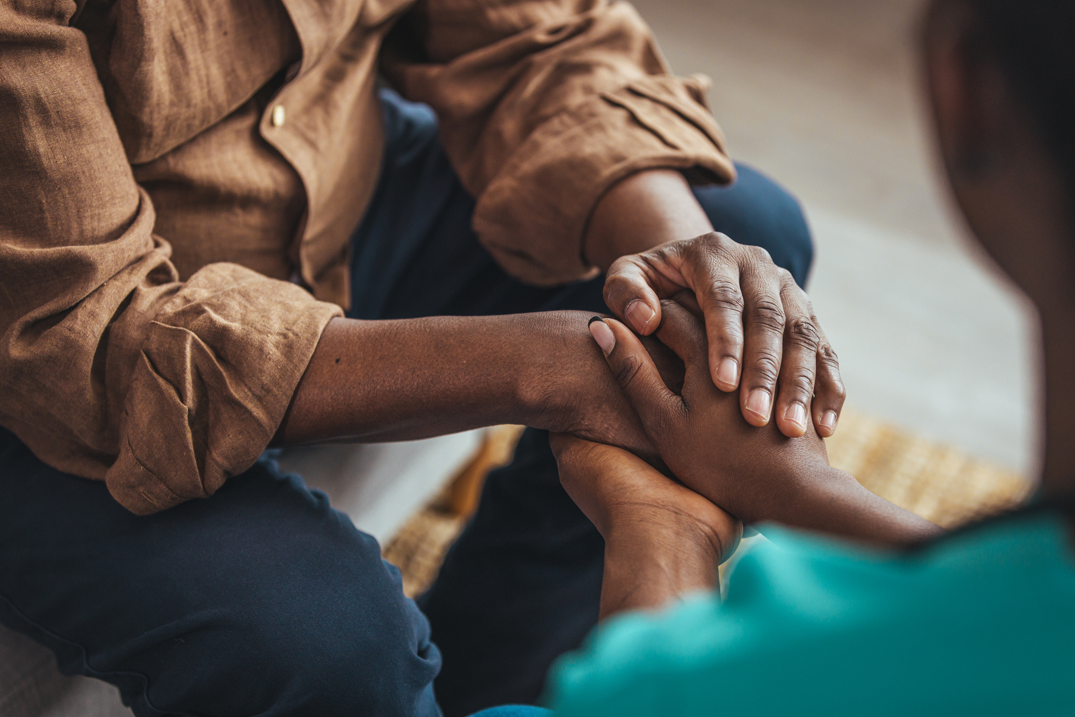 Closeup shot of a young woman holding a senior man's hands in comfort.